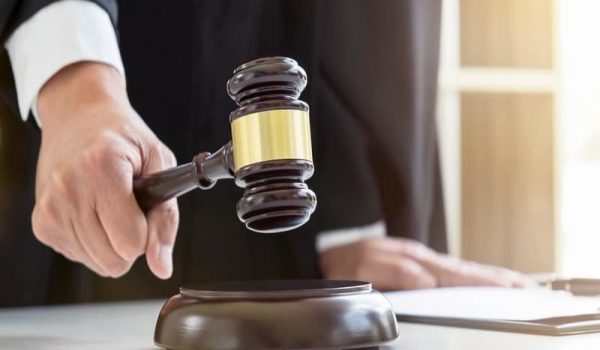 Close up of Male lawyer or judge hand’s striking the gavel on sounding block, working with Law books, report the case on table in modern office, Law and justice concept Close up of Male lawyer or judge hand's striking the gavel on sounding block, working with Law books, report the case on table in modern office, Law and justice concept.